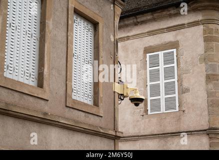 Surveillance camera in the street. Surveillance camera hanging on the wall. Security concept. Face recognition. Search programs for criminals. Stock Photo
