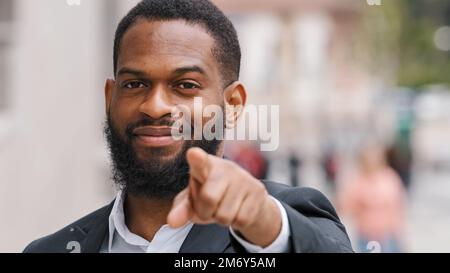 Close up ethnic African American man entrepreneur employer male HR manager CEO businessman in city outdoors pointing with forefinger direction to Stock Photo