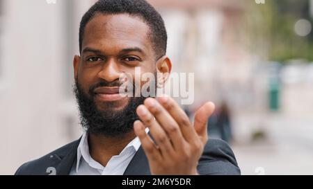 Headshot ethnic African American man entrepreneur employer male HR manager CEO businessman invite to come welcoming hand gesture inviting candidate at Stock Photo