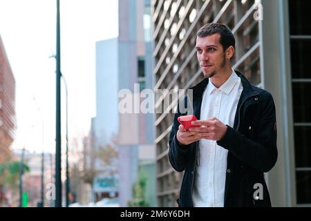 Man using a mobile phone while standing outdoors. Stock Photo