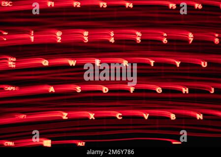 Light painting keyboard letters and numbers. Beautiful colorful background. Long exposure light painting,red color curved lines in vibrant neon. Stock Photo