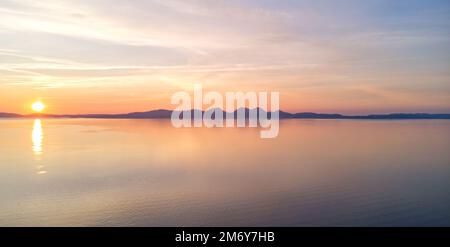 View of The Paps of Jura, Isle of Jura, and the Isle of Islay, Hebrides, Scotland from The Isle of Gigha at sunset Stock Photo