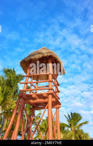 Wooden lifeguard tower on a Caribbean beach against the sky with coconut palm trees in background. Stock Photo