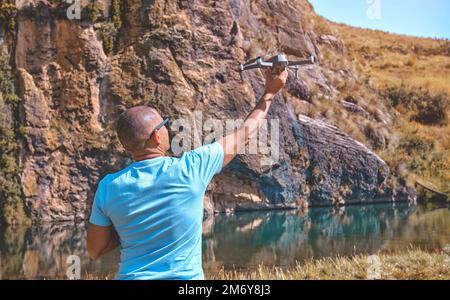 Young man with modern drone in mountains, back view Stock Photo