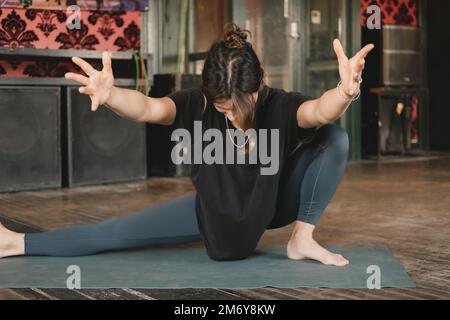 Woman yogi new teacher young adult balancing a skandasana pose extending and holding her arms in the air with green leggings during her yoga practice Stock Photo