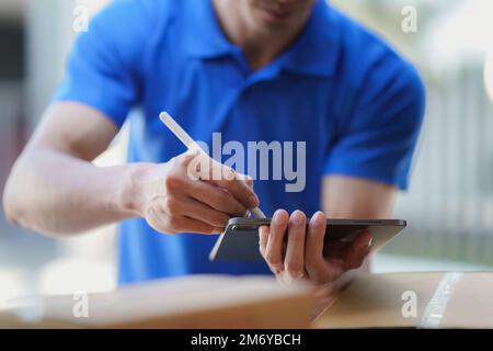 Asian courier with parcel and delivery logistic concept. Delivery man using digital tablet Stock Photo
