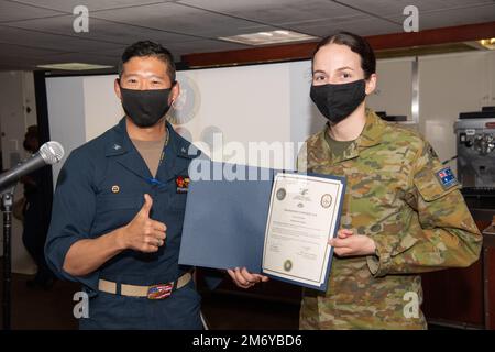 PACIFIC OCEAN (May 10, 2022) Captain Hank Kim, Pacific Partnership 2022 (PP22) mission commander (left), poses with Australian Army Captain Isabella Negus after a promotion ceremony aboard the Military Sealift Command hospital ship USNS Mercy (T-AH 19) while underway for PP22. Now, in its 17th year, Pacific Partnership is the largest annual multinational humanitarian assistance and disaster relief preparedness mission conducted in the Indo-Pacific. Stock Photo