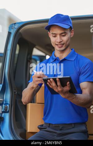 Asian courier with parcel and delivery logistic concept. Delivery man using digital tablet Stock Photo