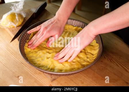 young caucasian woman hands push shortcrust pastry into a baking tin. Stock Photo
