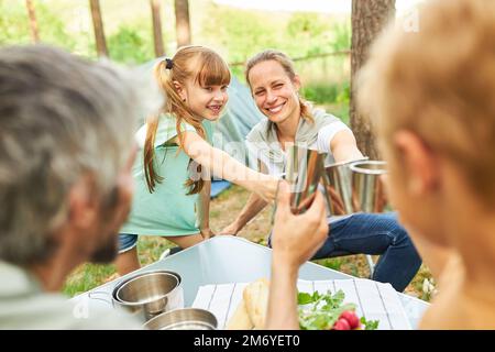 Smiling family toasting mugs while enjoying lunch during camp trip in forest Stock Photo