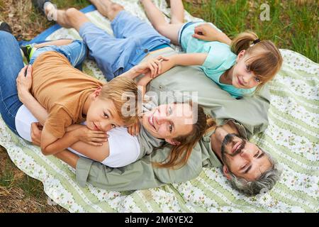 Portrait of children with parents lying on blanket at campsite during summer vacation Stock Photo