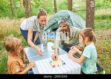 Mother and father playing board game with children on table in campground Stock Photo