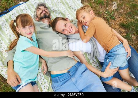 Portrait of parents with daughter and son lying on blanket in forest during summer holiday Stock Photo