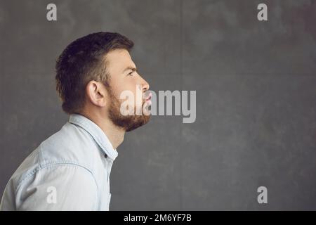 Profile portrait of a man pouting lips giving a smooch or blowing an air kiss at the empty side Stock Photo