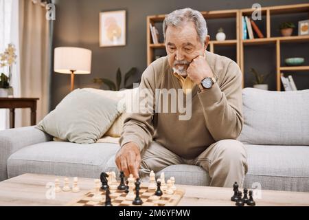 Senior man, thinking or playing chess in house, home living room or apartment in Japanese strategy, checkmate or board game contest. Retirement Stock Photo