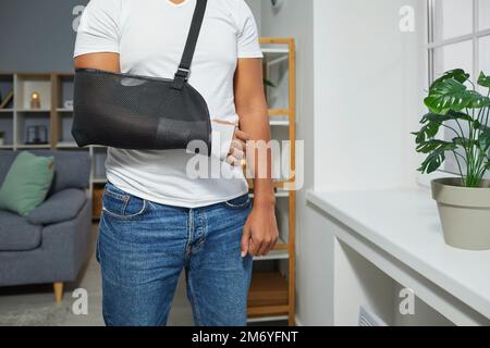 Young man wears a medical arm sling and a bandage to take care of his injured wrist Stock Photo