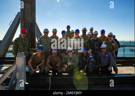 PERTH, Australia (April 20, 2022) – Sailors assigned to the Emory S. Land-class submarine tender USS Frank Cable (AS 40) and Royal Australian Navy sailors, pose for a group photo following a weapons handling training exercise with a Tomahawk training shape aboard the ship at HMAS Stirling Navy Base on Garden Island off the coast of Perth, Australia, April 20, 2022. Frank Cable is currently on patrol conducting expeditionary maintenance and logistics in support of national security in the U.S. 7th Fleet area of operations. Stock Photo