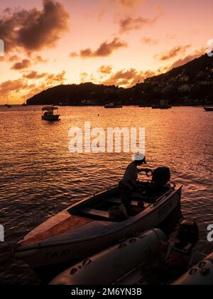 Bequia, Admiralty Bay, Port Elizabeth. A dinghy moored at sunset visiting shore restaurants from yacht in bay. Stock Photo