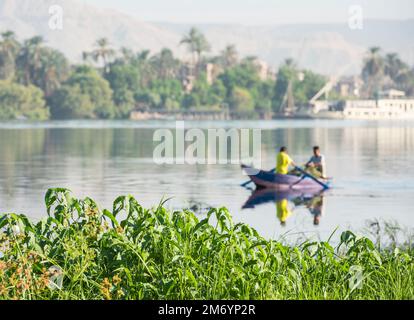 Traditional egyptian bedouin fisherman in rowing boat on river Nile fishing by riverbank Stock Photo