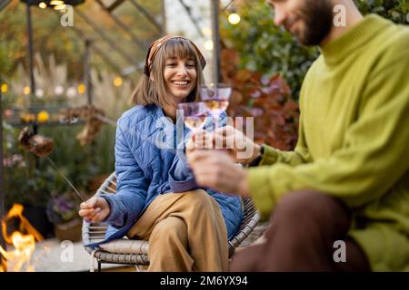 Young couple spending dinner time by the fire at backyard Stock Photo