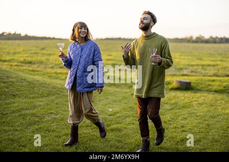 Couple hang out together, walking on green field on sunset Stock Photo