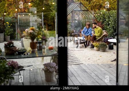 Young couple spending dinner time by the fire at backyard Stock Photo