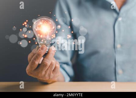 Business man holding Light bulbs with futuristic Brain inside. Innovative technology and creativity idea concept. Stock Photo