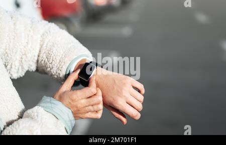 Female person using her smartwatch outdoors. Stock Photo