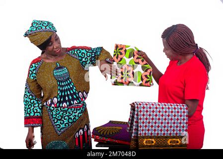 portrait of two beautiful women looking at several different models of traditional loincloths while smiling. Stock Photo
