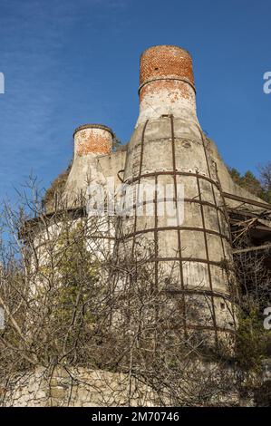 Castelveccana, Italy- 12-27-2022: Red brick chimneys and abandoned furnaces with vegetation covering them in Caldè on Lake Maggiore Stock Photo