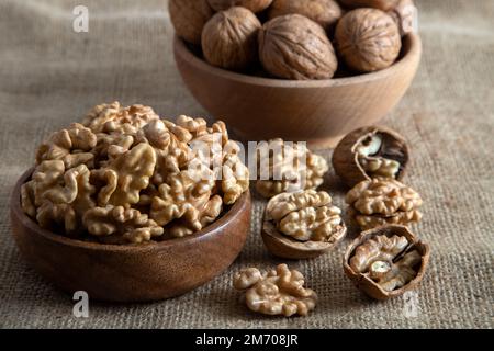 Peel walnuts and whole walnuts on burlap sack,closeup Stock Photo