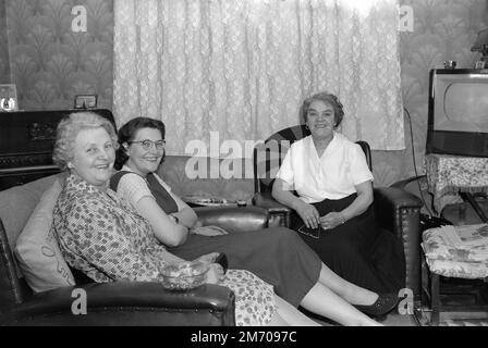 1950s, historical, three ladies sitting together in a front room, a televison set of the era in the corner, England, UK, an EKCO television. Founded in 1924, in Southend-on-Sea, EKCO was a British electronics company, named after its founder Eric Kirkham Cole. E. K Cole Ltd, began making radio sets and then during WWII developed a warning radar system. Production of television sets began in the early 50s and by 1957, they had manufactured a million sets. EKCO merged with another British electronics company, the cambridge based PYE in 1960 to form British Electronics Industries Ltd. Stock Photo
