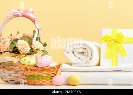 Stack of white bed linen and rolls of towels with easter decor on the table Stock Photo