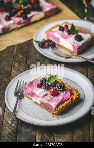 Cheesecake slices and berries on serving plates with forks Stock Photo
