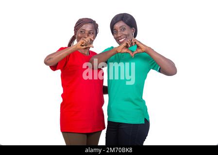 two mature women gesturing with one hand. Woman in green T-shirt making a heart shape with her hands and the other making a "C" gesture with her hand. Stock Photo