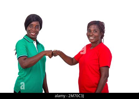 beautiful women in colored t-shirts standing on white background making fists and looking at camera smiling. Stock Photo