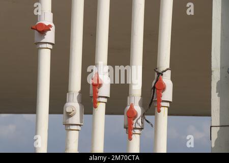 The water valve connects to a PVC pipe on the rooftop of a building for water supply. Ball valve and PVC water pipes for regulated water flow Stock Photo