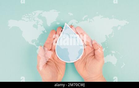 Holding a water drop in the hands, silhouette of world map, environment issue, scarcity of resources, world water day Stock Photo