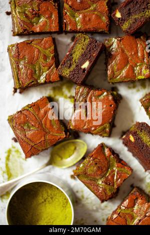 Squares of matcha chocolate brownie with a tin of matcha powder. Stock Photo