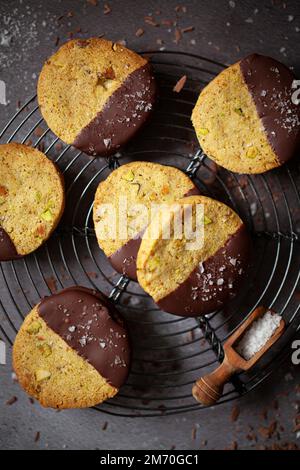Pistachio shortbread cookies half dipped in chocolate and sprinkled with sea salt. Stock Photo