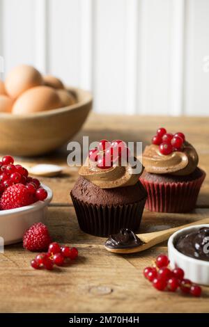 Chocolate cupcakes with red fruit on wooden table Stock Photo