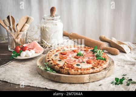 Ham and mozzarella pizza on a cutting board Stock Photo