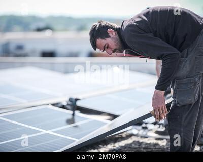 Male team engineers installing stand-alone solar photovoltaic panel ...