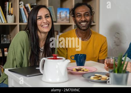 Happy young friends having a break in coffee shop, multiracial universitary student having fun during breakfast Stock Photo