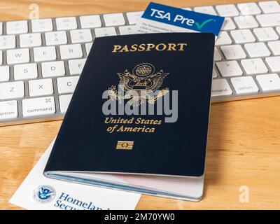 United States of America Passport with Department of Homeland Security TSA Pre Check registration information card. US Passport on desk with computer. Stock Photo