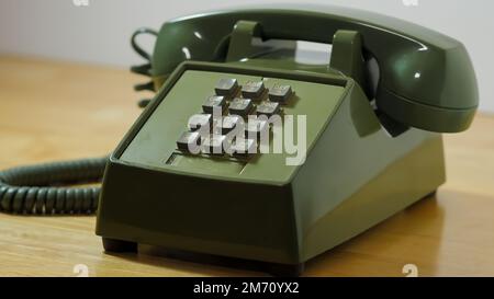 Retro push button rotary dial telephone. Vintage avocado green landline phone. Stock Photo