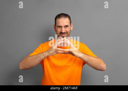 Evil genius, scheming man, making plans, looking cunning and thoughtful, mastermind idea, tipping fingers while thinking, standing against gray Stock Photo