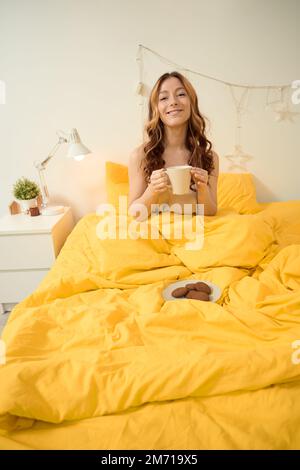 Cheerful lady enjoying her morning meal in bedroom Stock Photo