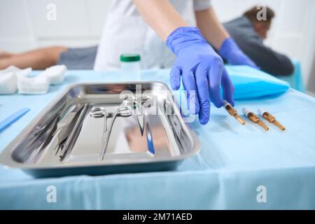 Nurse takes an ampoule of medicine from the manipulation table Stock Photo