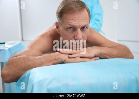 Man lies calmly on his stomach on the operating table Stock Photo